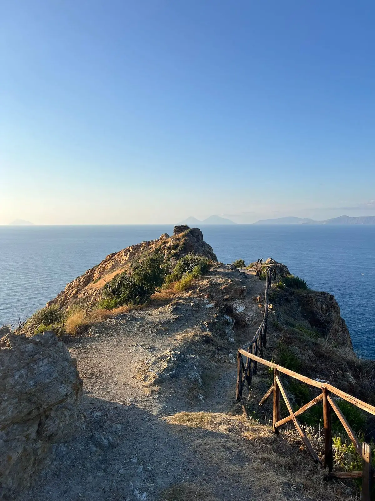 Il crinale roccioso di Capo Calavà che scende verso il mare, con le Eolie all'orizzonte