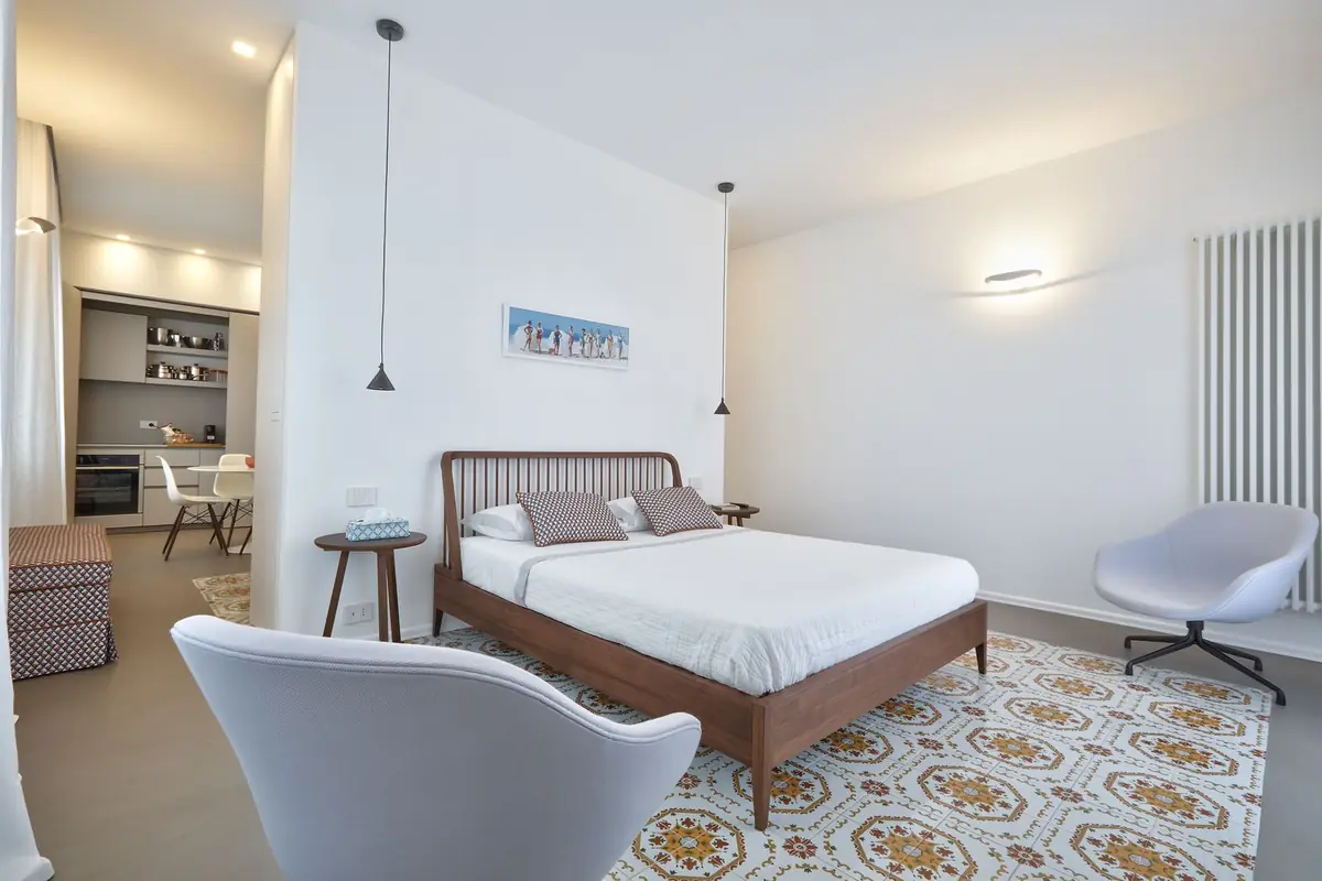 Arancio apartment: walnut bed and inlaid Sicilian-majolica floor rug
