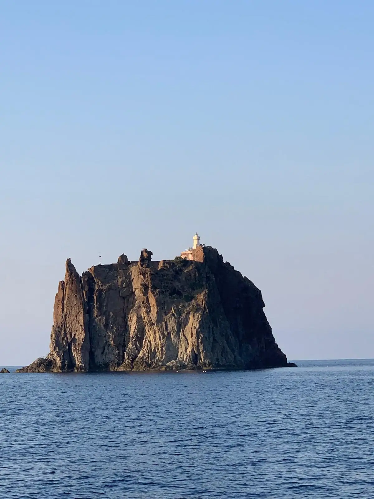 The rock of Strombolicchio close up, with the white lighthouse on its summit