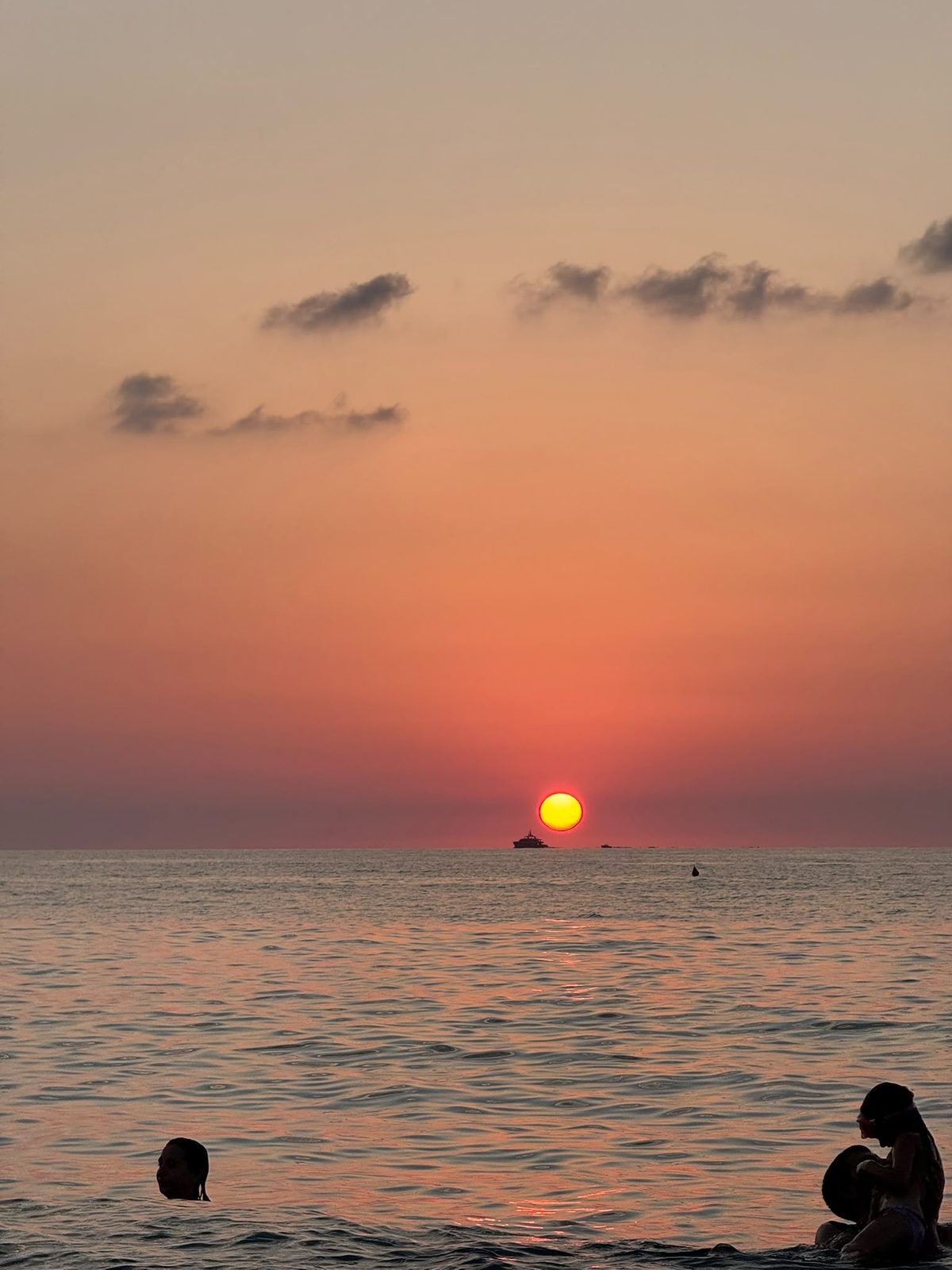 Chi fa il bagno mentre il sole si spegne in mare