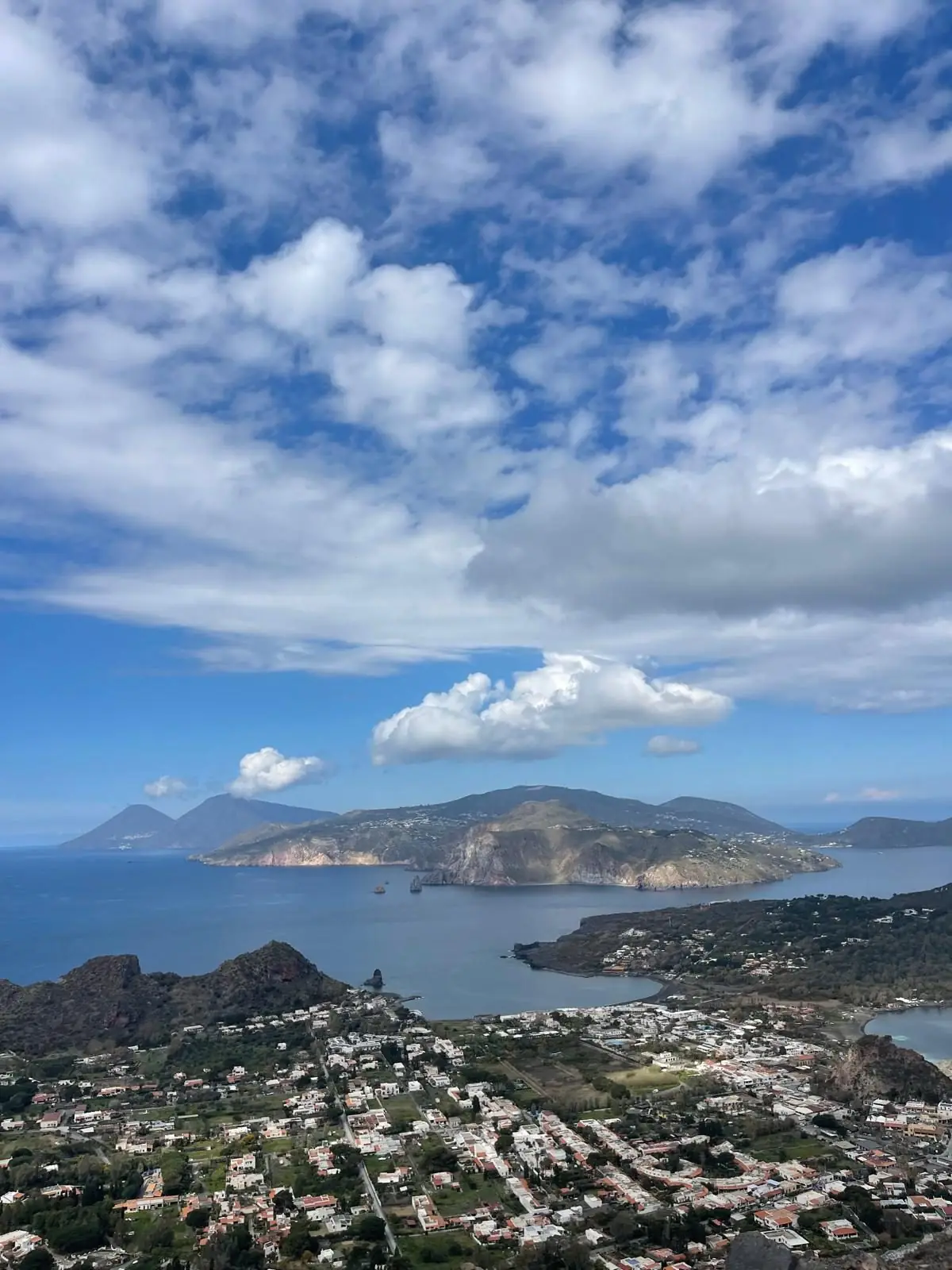 The same panorama under a sky full of cloud, the village below and the archipelago lined up to the north